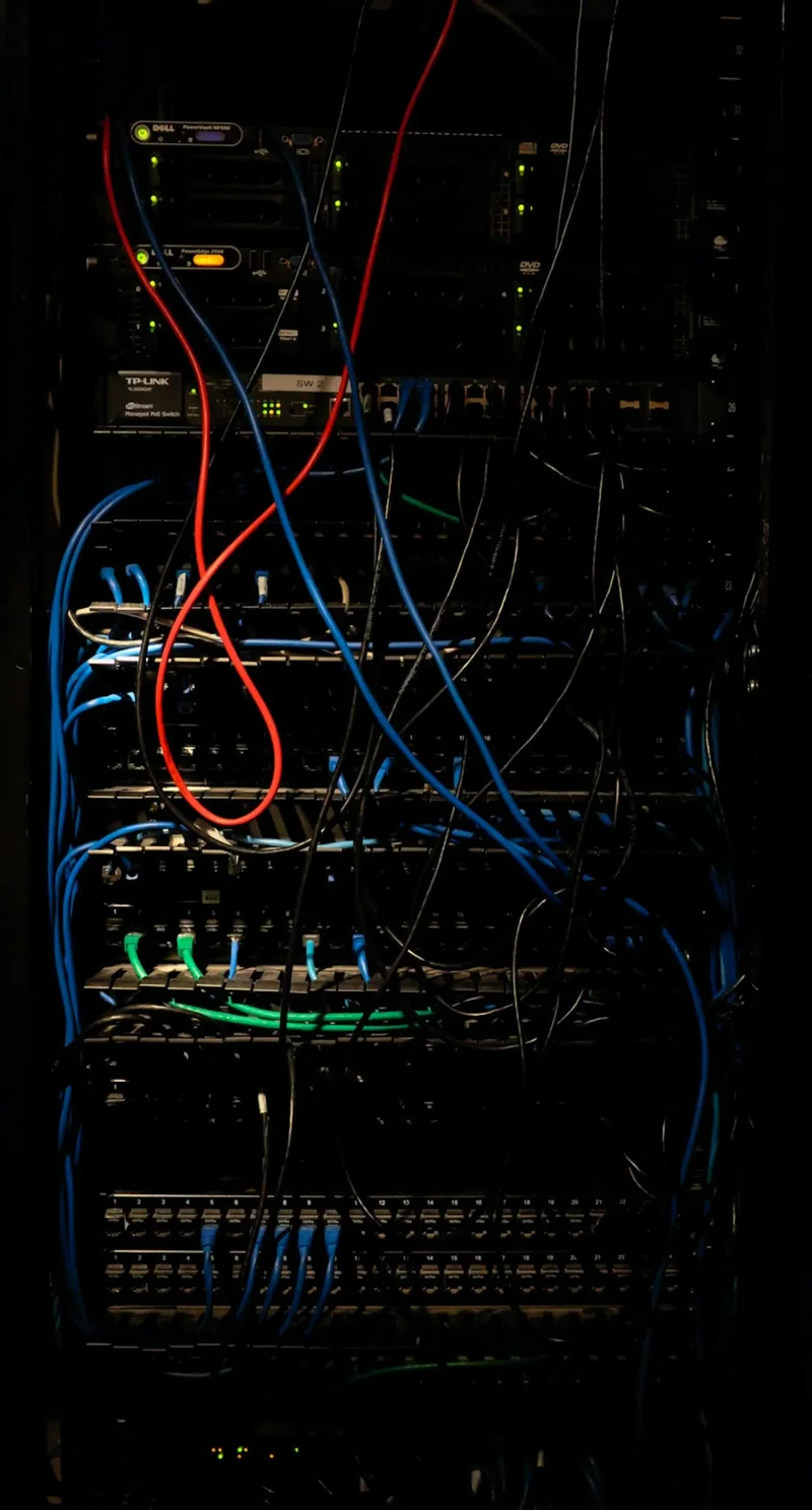 A dark server rack threaded with blue network cables